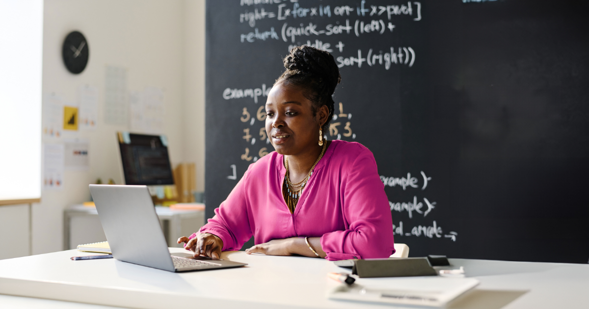 A teacher sitting at her desk, using a computer