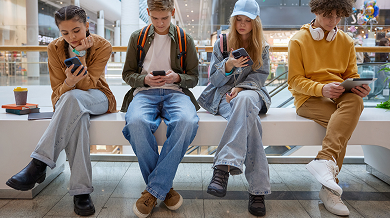 Teens sitting in a shoping mall looking at their phones