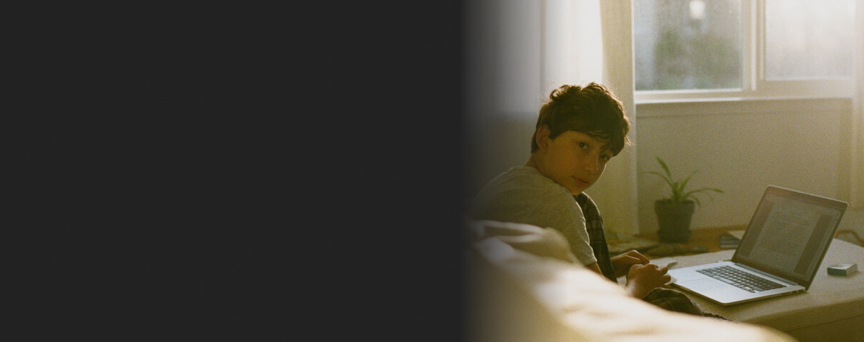 boy with laptop looks over shoulder